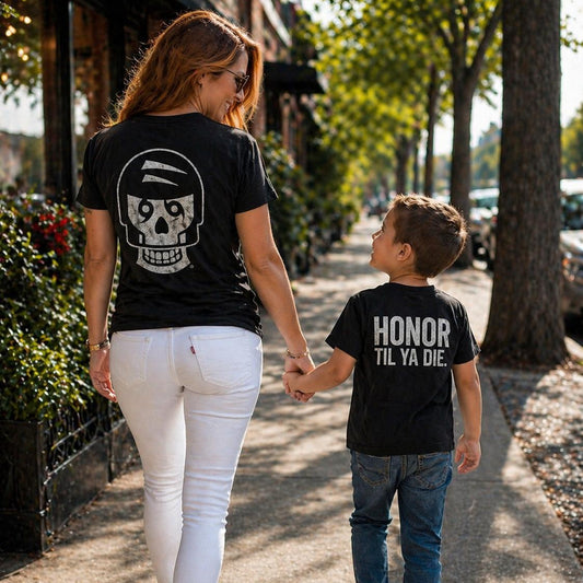 Woman and child walking on a sidewalk wearing black Honor Til Ya Die t-shirts with Nola Til Ya Die skull and text designs.