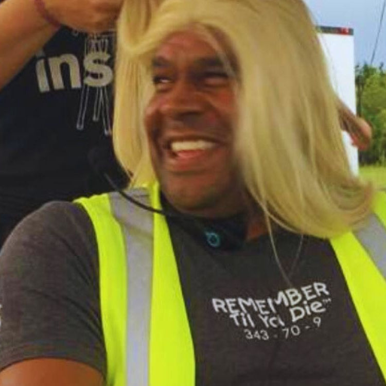 Recon Marine John Keller wearing a blonde wig on a movie set with 9/11 Remember Til Ya Die t-shirt.