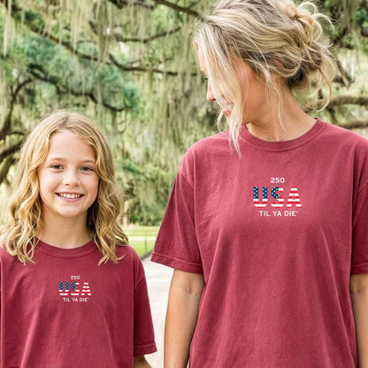 Two people wearing matching red t-shirts with USA Til Ya Die on the front of the Nola Til Ya Die tee.