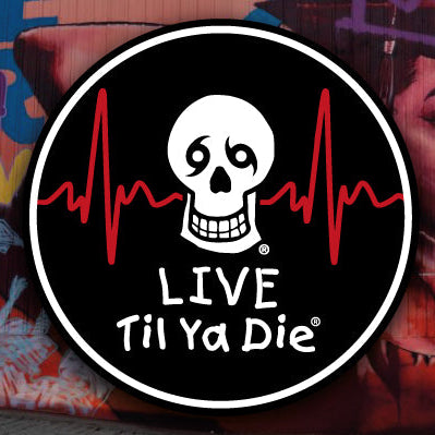 A circular black sticker or decal with a white skull, red heartbeat line, and the text 'LIVE Til Ya Die' is shown against a colorful graffiti wall.